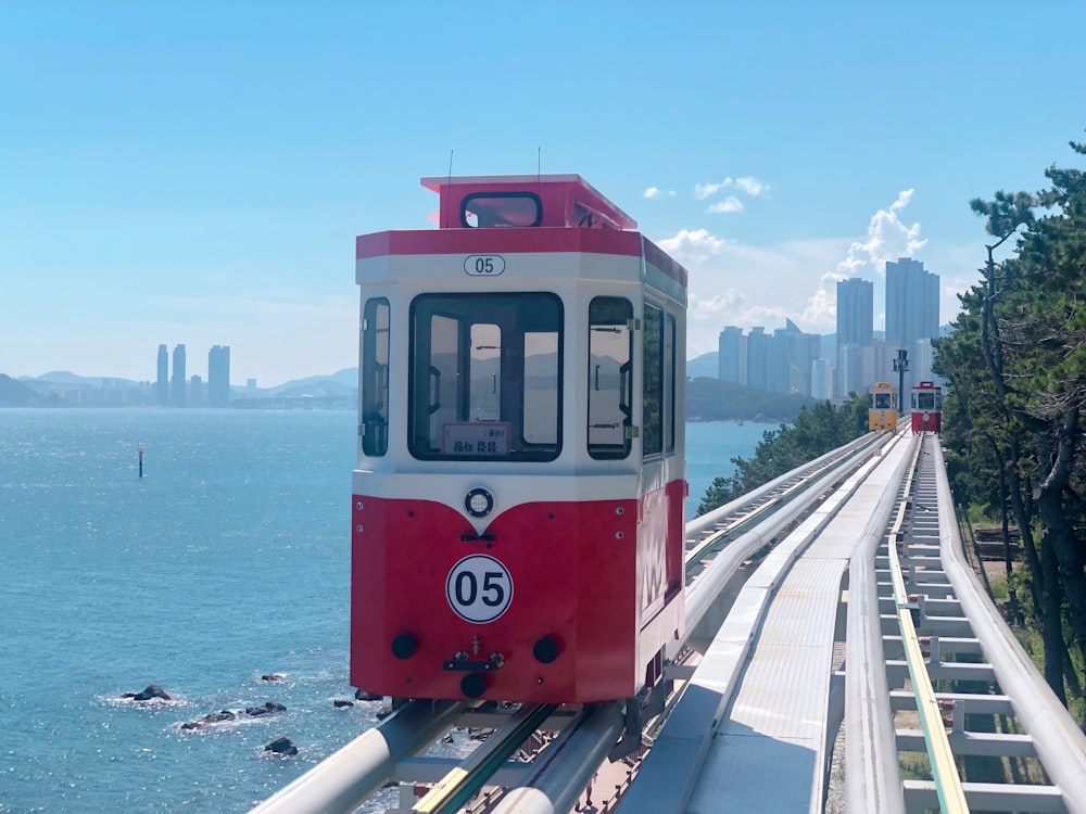 um trem vermelho e branco viajando sobre uma ponte