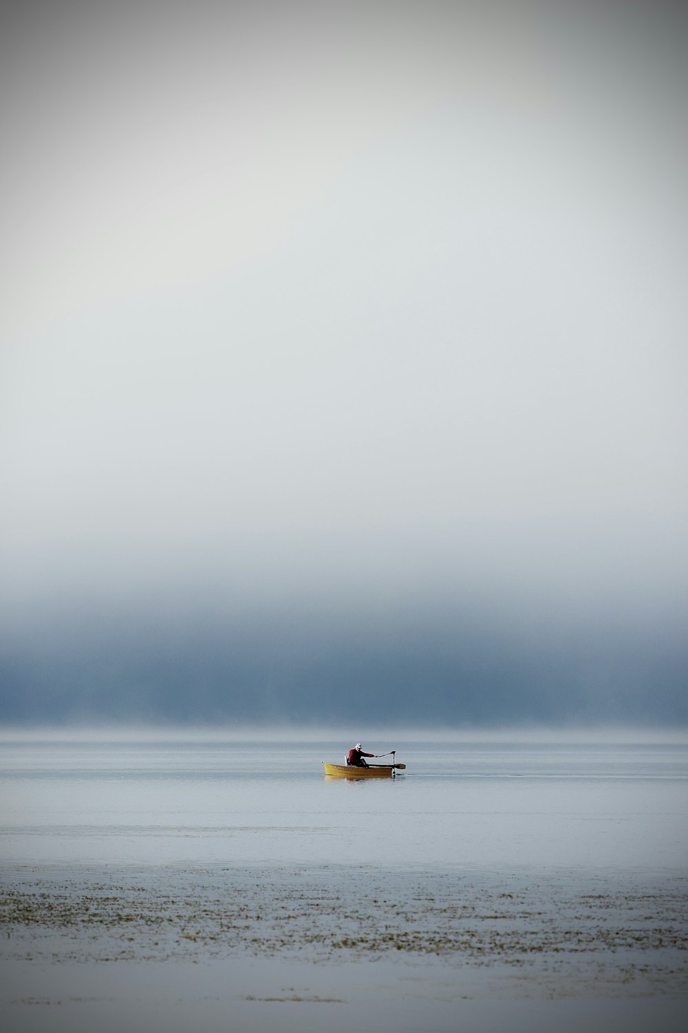 a lone boat floating in the middle of a large body of water