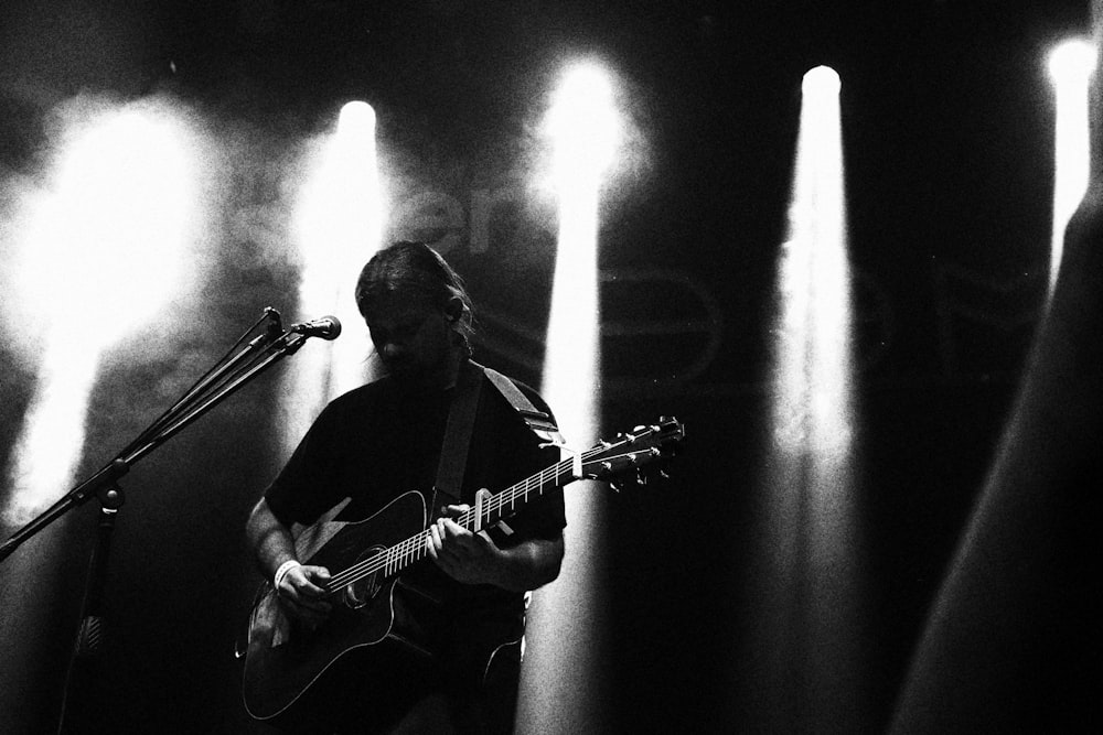 a black and white photo of a man playing a guitar