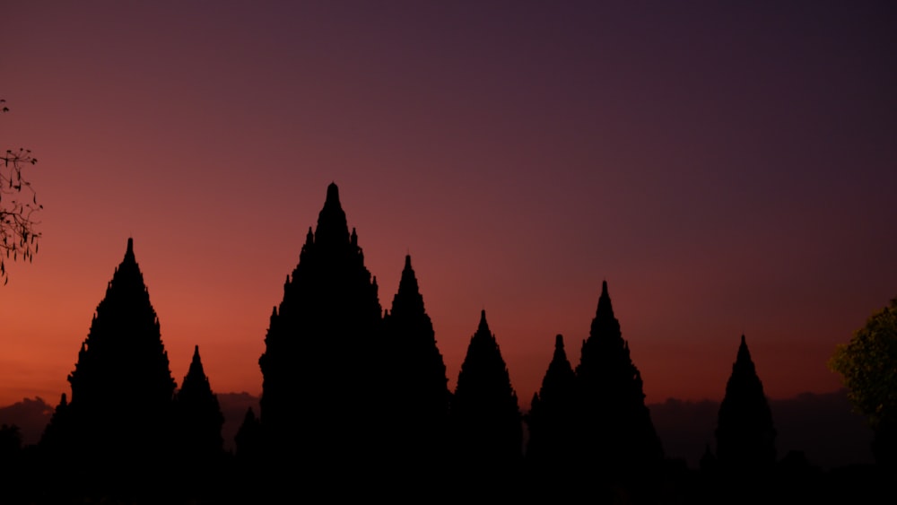 a group of spires silhouetted against a sunset