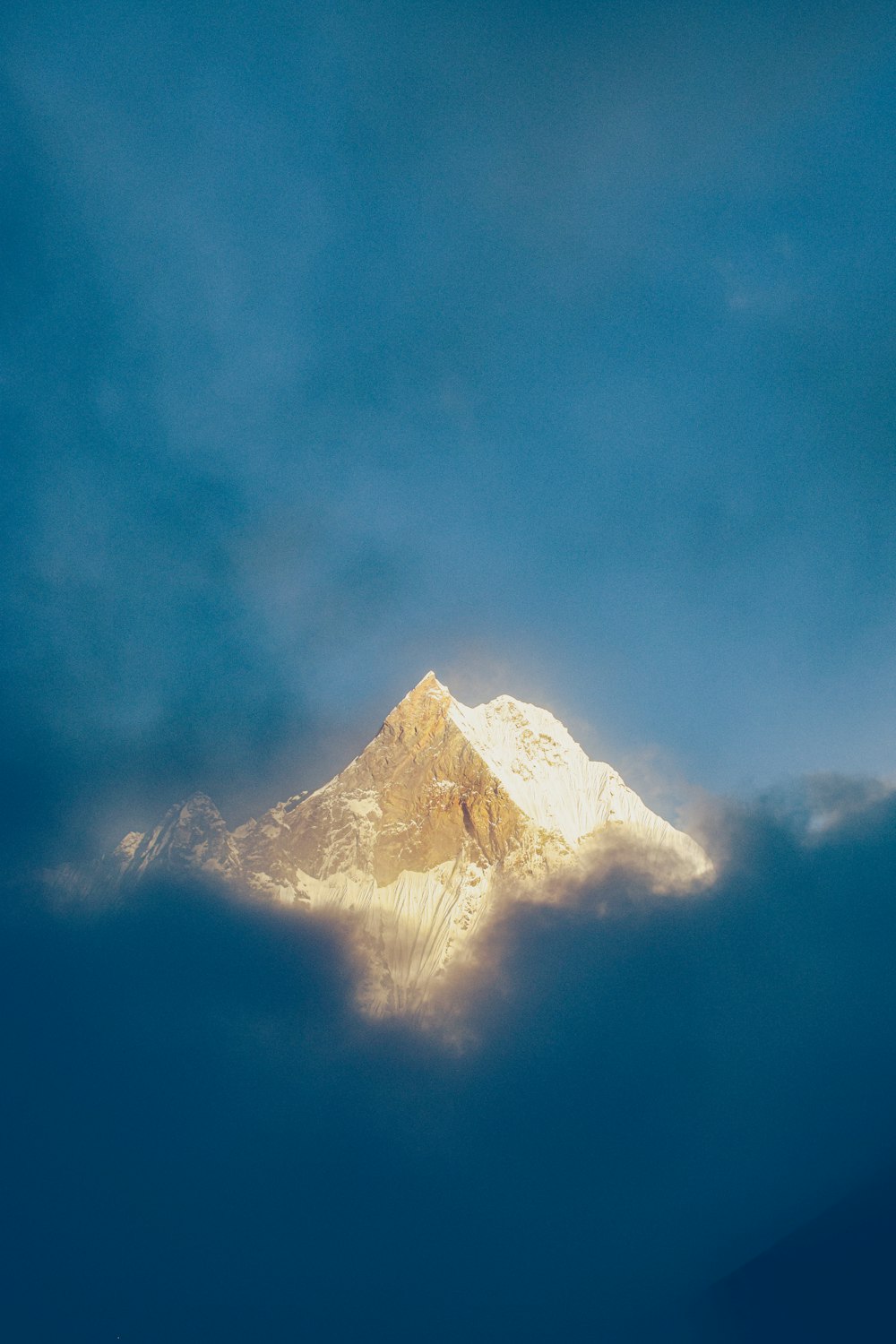 a snow covered mountain is seen through the clouds