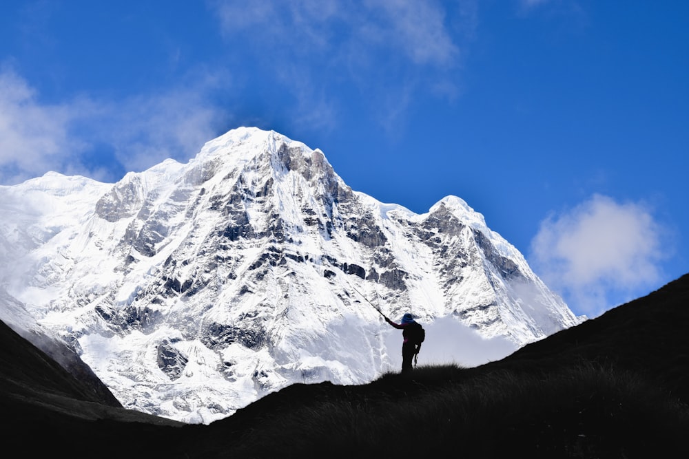 eine Person, die auf einem Hügel mit einem Berg im Hintergrund steht