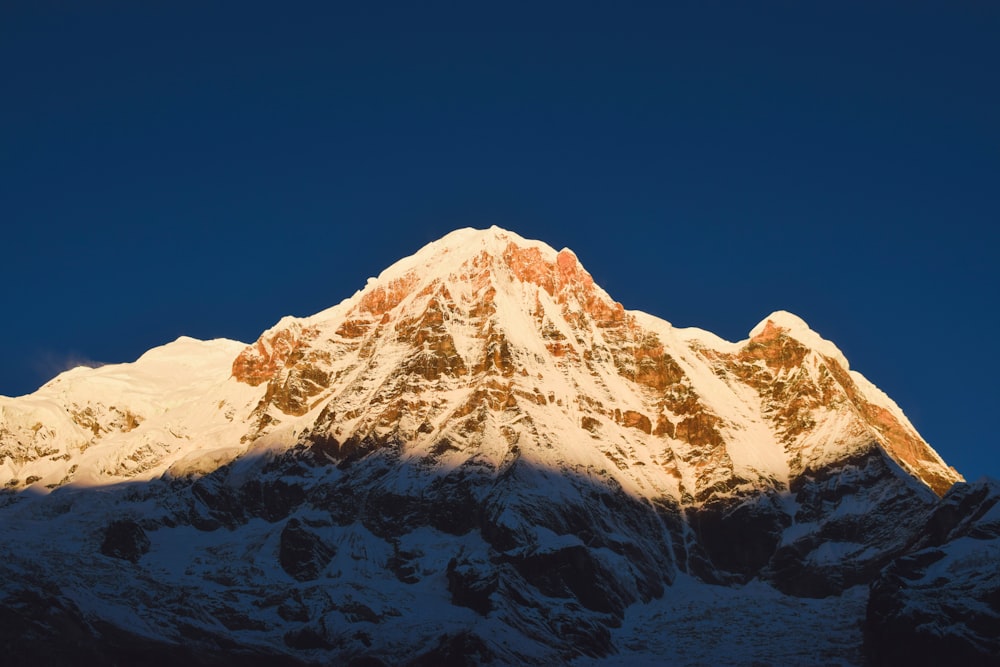 the top of a snow covered mountain against a blue sky