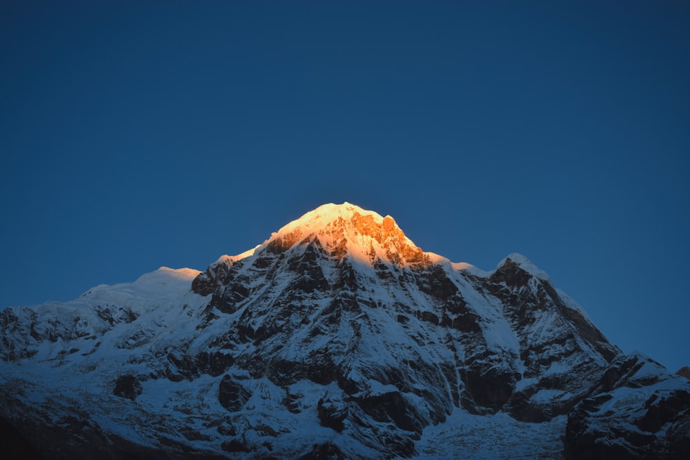 Une montagne enneigée avec un ciel bleu en arrière-plan