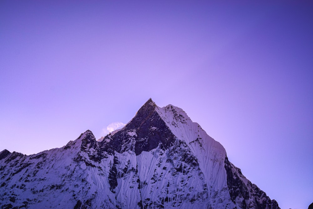 a snow covered mountain under a purple sky