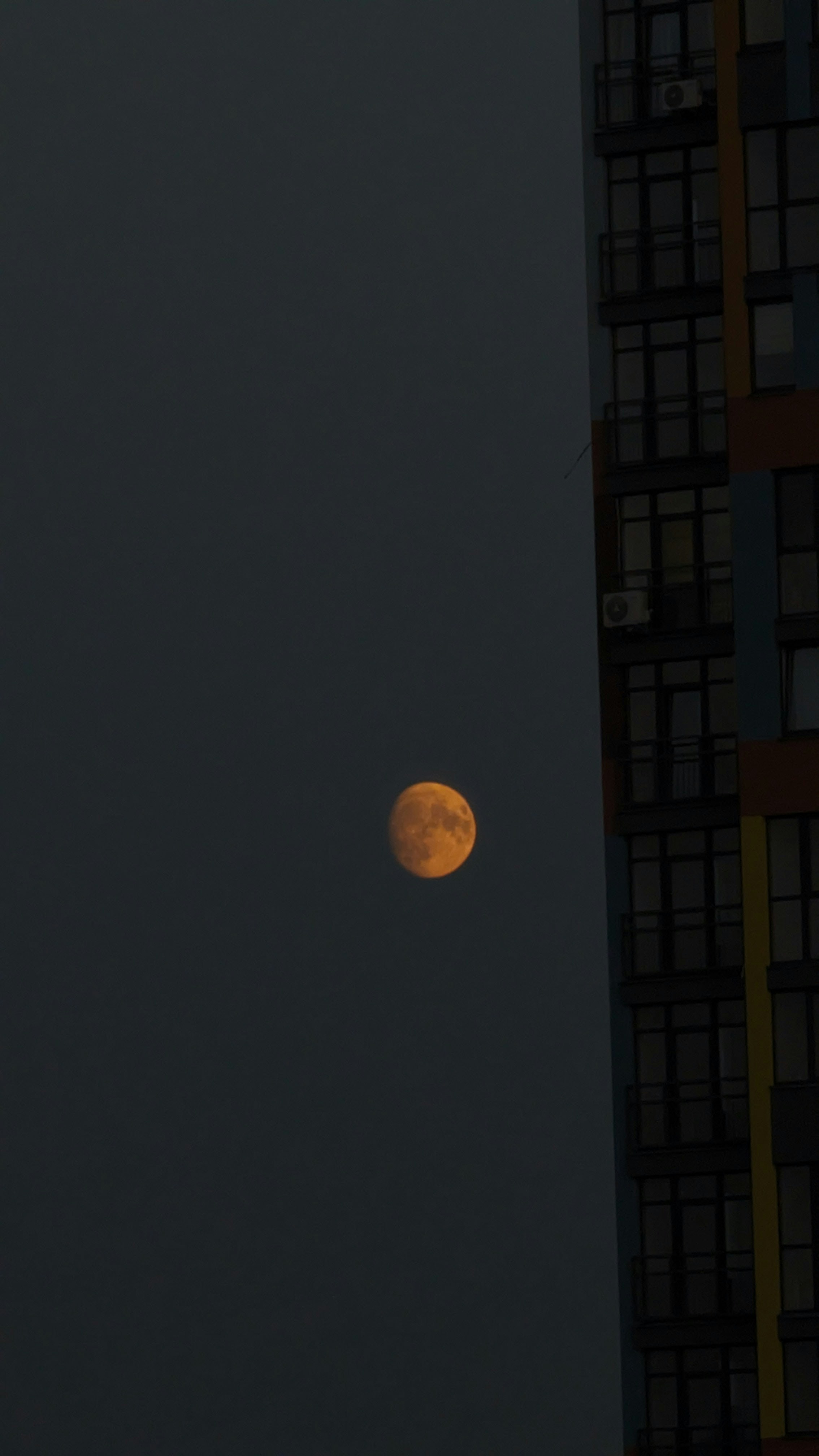 A full moon is seen in the sky above a tall building photo – Free Moon ...