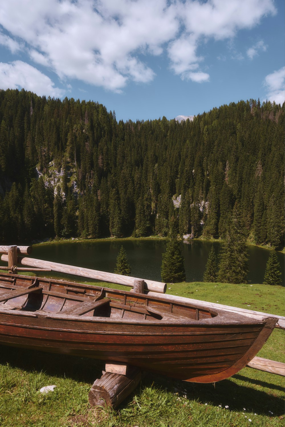 a wooden boat sitting on top of a lush green field