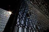 Architectural metal facade with intricate geometric patterns catching sunlight.