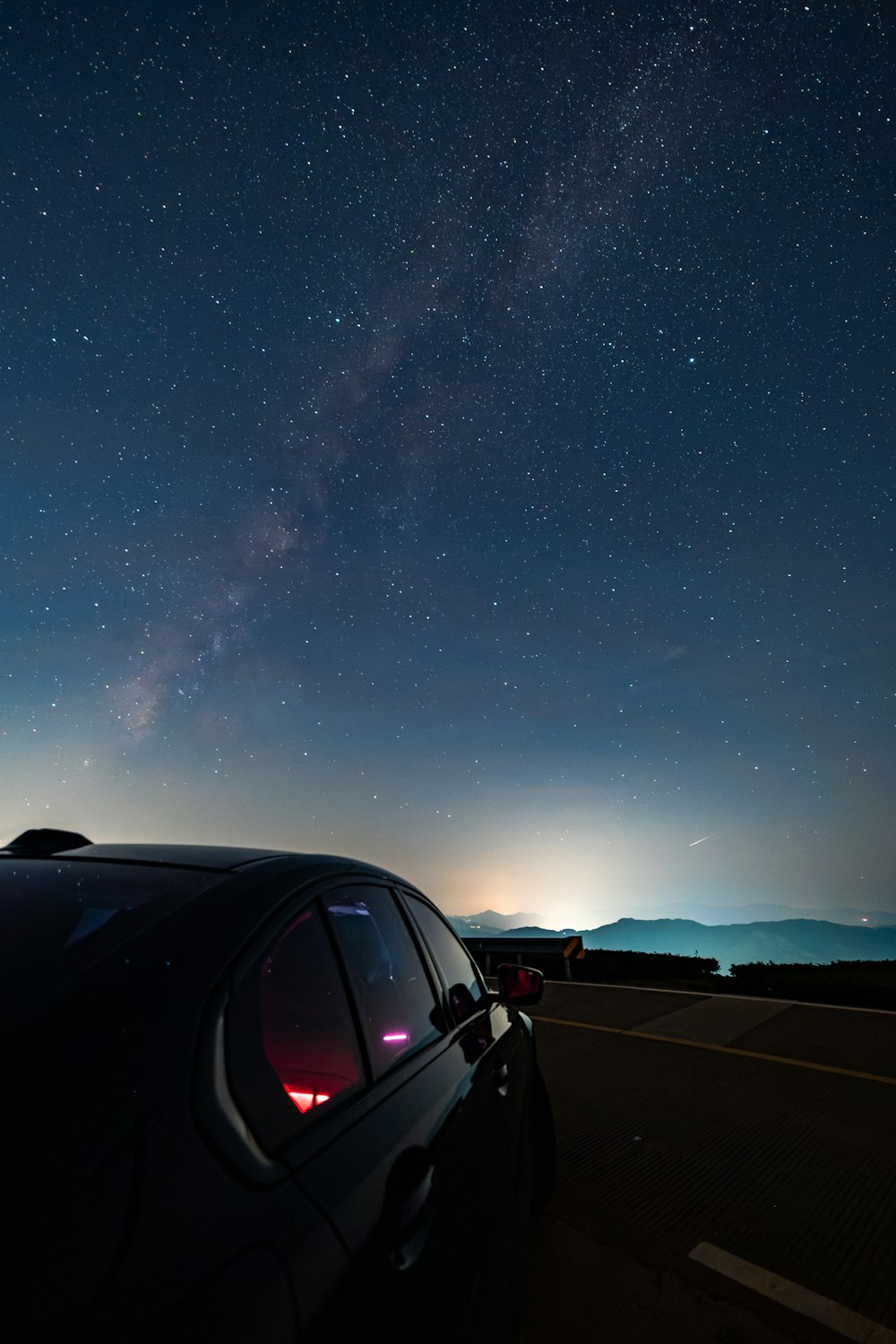 a car parked on the side of a road under a night sky filled with stars