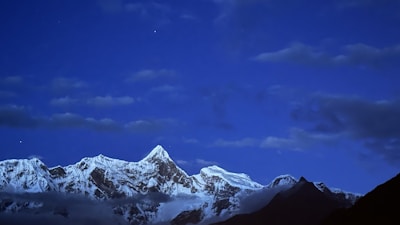 A panoramic view of snow-capped Himalayan peaks under a deep twilight sky, inviting adventure.