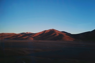 A spacious lot with a gentle slope, framed by distant mountains and a vibrant sunset.