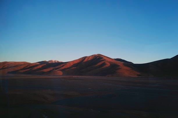 A spacious lot with a gentle slope, framed by distant mountains and a vibrant sunset.