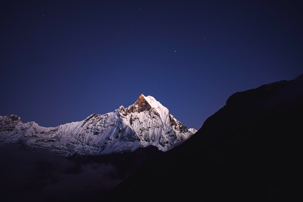 a mountain covered in snow under a night sky