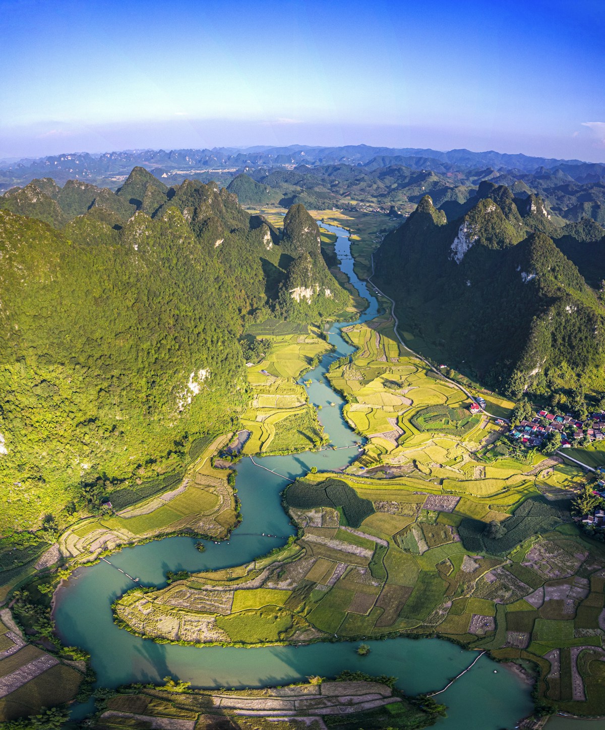 Rio serpenteando por um vale verdejante entre montanhas, com a luz suave do dia banhando a paisagem — evocando o rio Jordão que Moisés contemplou de longe e a terra prometida que ele não atravessaria, em Deuteronômio 31
