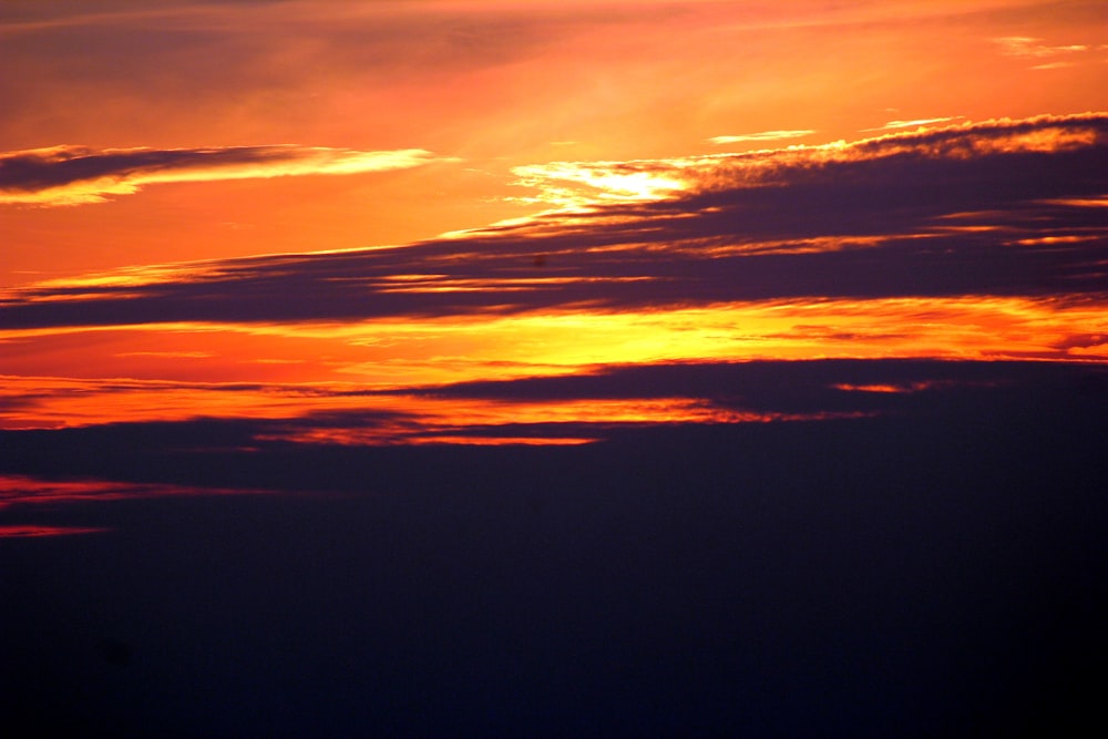 a plane flying in the sky at sunset