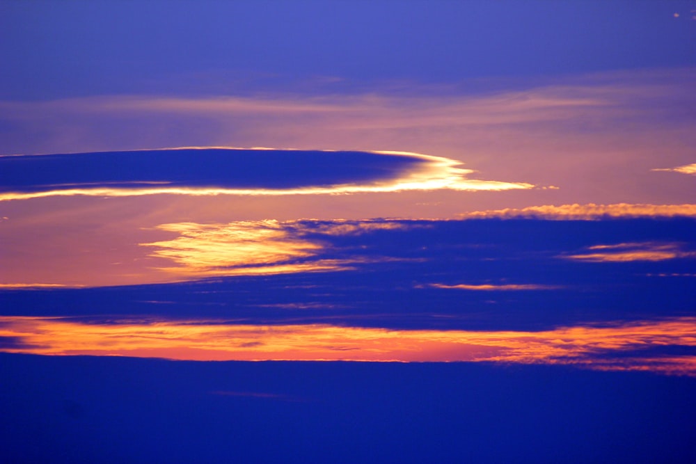 a plane flying in the sky at sunset