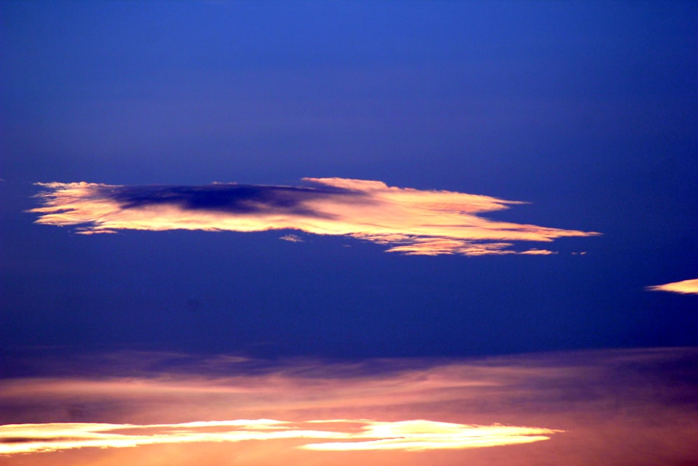 a plane flying in the sky at sunset