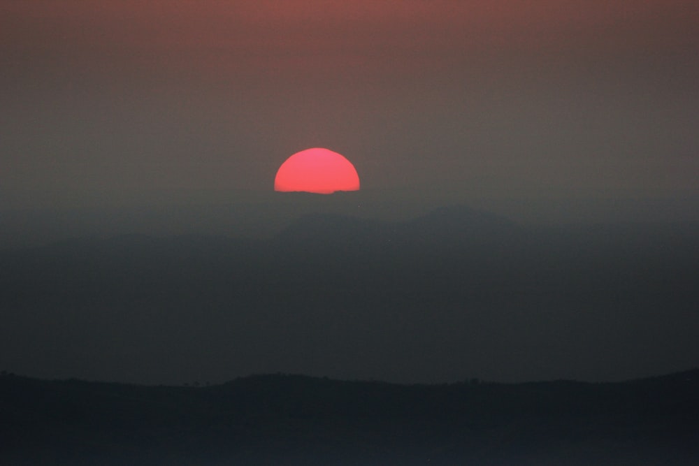 the sun is setting over a mountain range