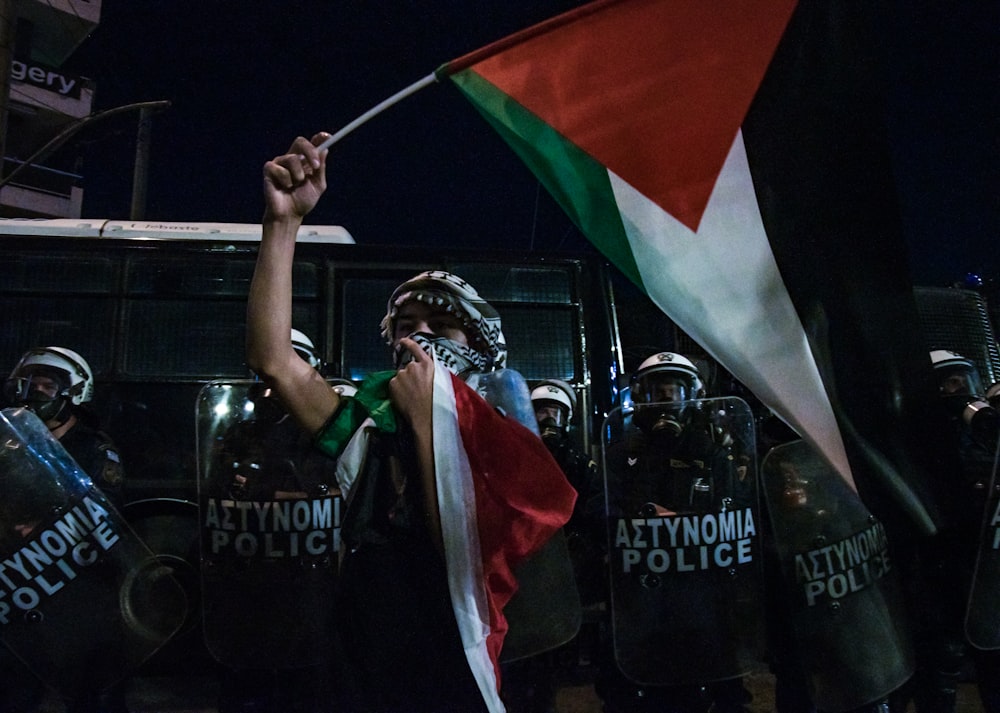 a person holding a flag in front of riot police