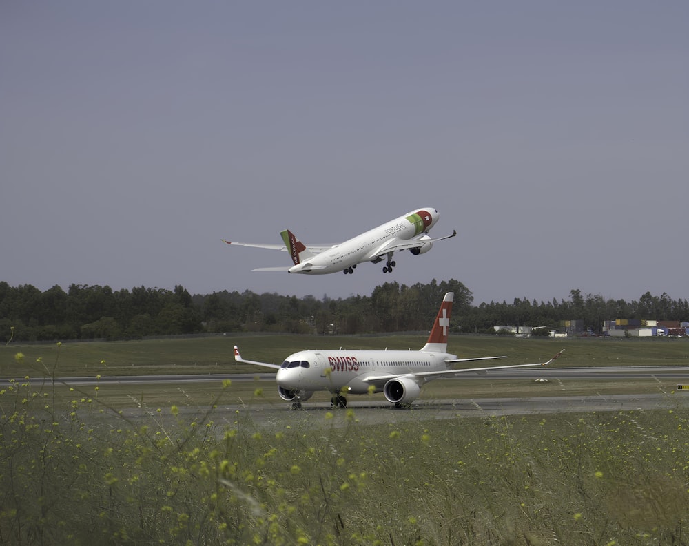 Zwei Flugzeuge fliegen im Tiefflug über eine Landebahn