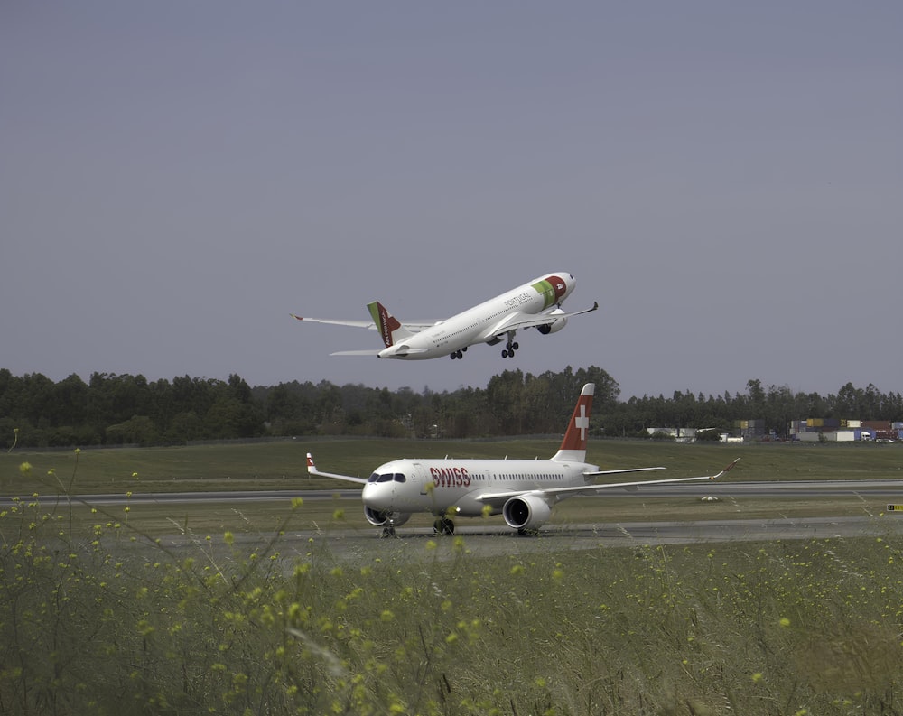 two airplanes are flying low over a runway