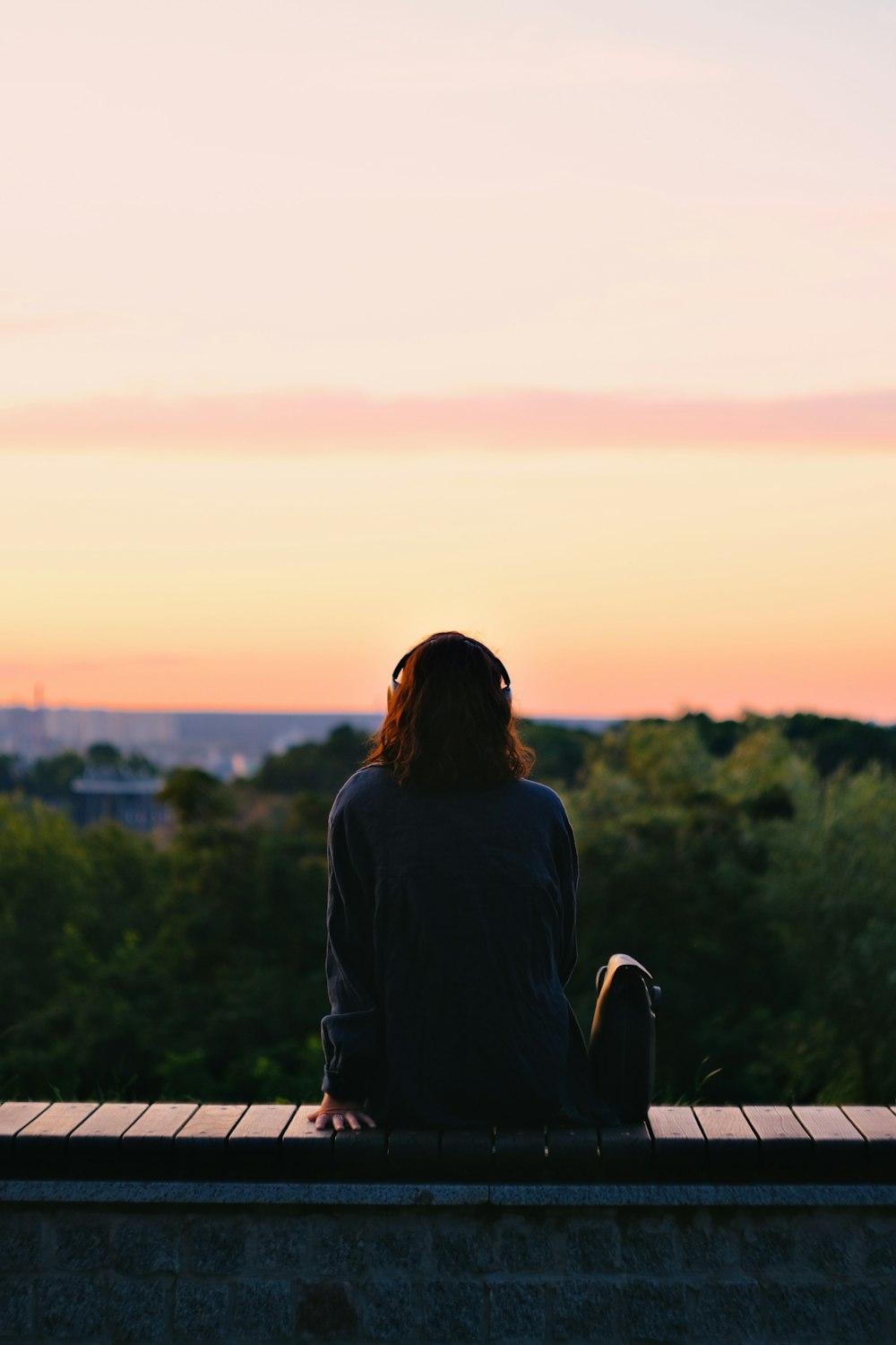 una persona sentada en una cornisa mirando la puesta de sol
