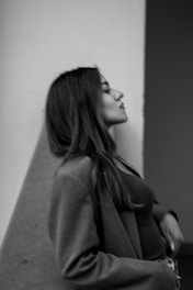 A black and white profile portrait of a woman with long hair, wearing a jacket. She is gazing upwards with a serene expression.