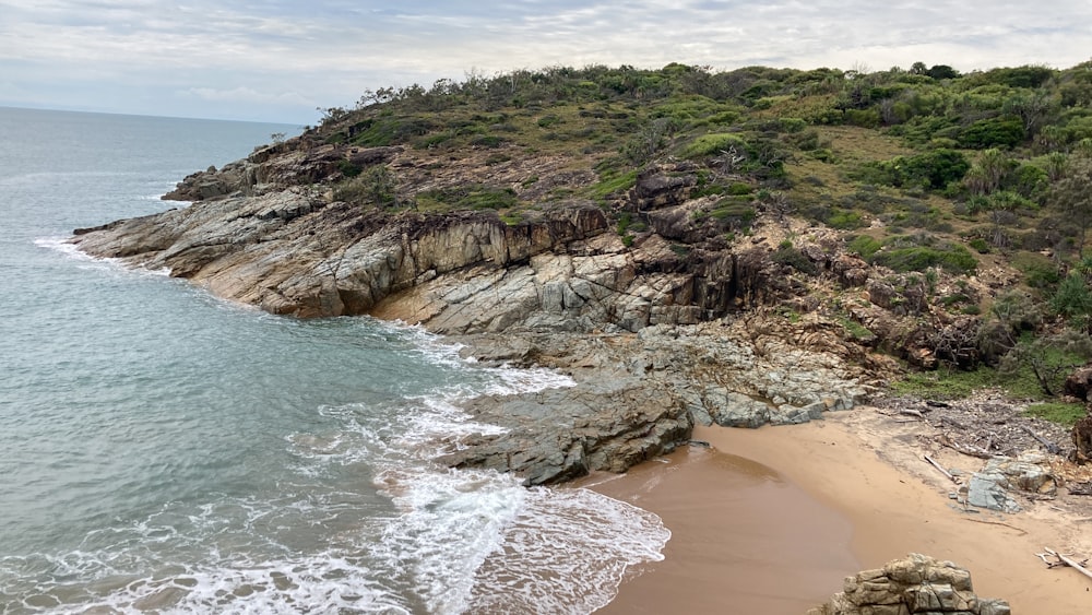 a sandy beach next to a rocky cliff