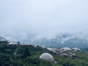 A serene outdoor dome accommodation surrounded by lush greenery and mountains.