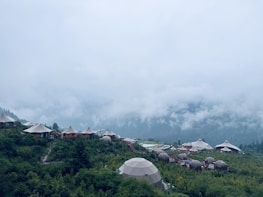 A serene outdoor dome accommodation surrounded by lush greenery and mountains.