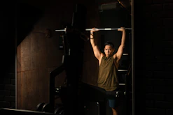 A focused athlete lifting heavy weights in a sleek gym setting under dramatic lighting.