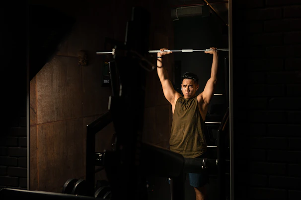 Photo of a focused athlete lifting weights inside a modern gym with dark tones and red highlights.