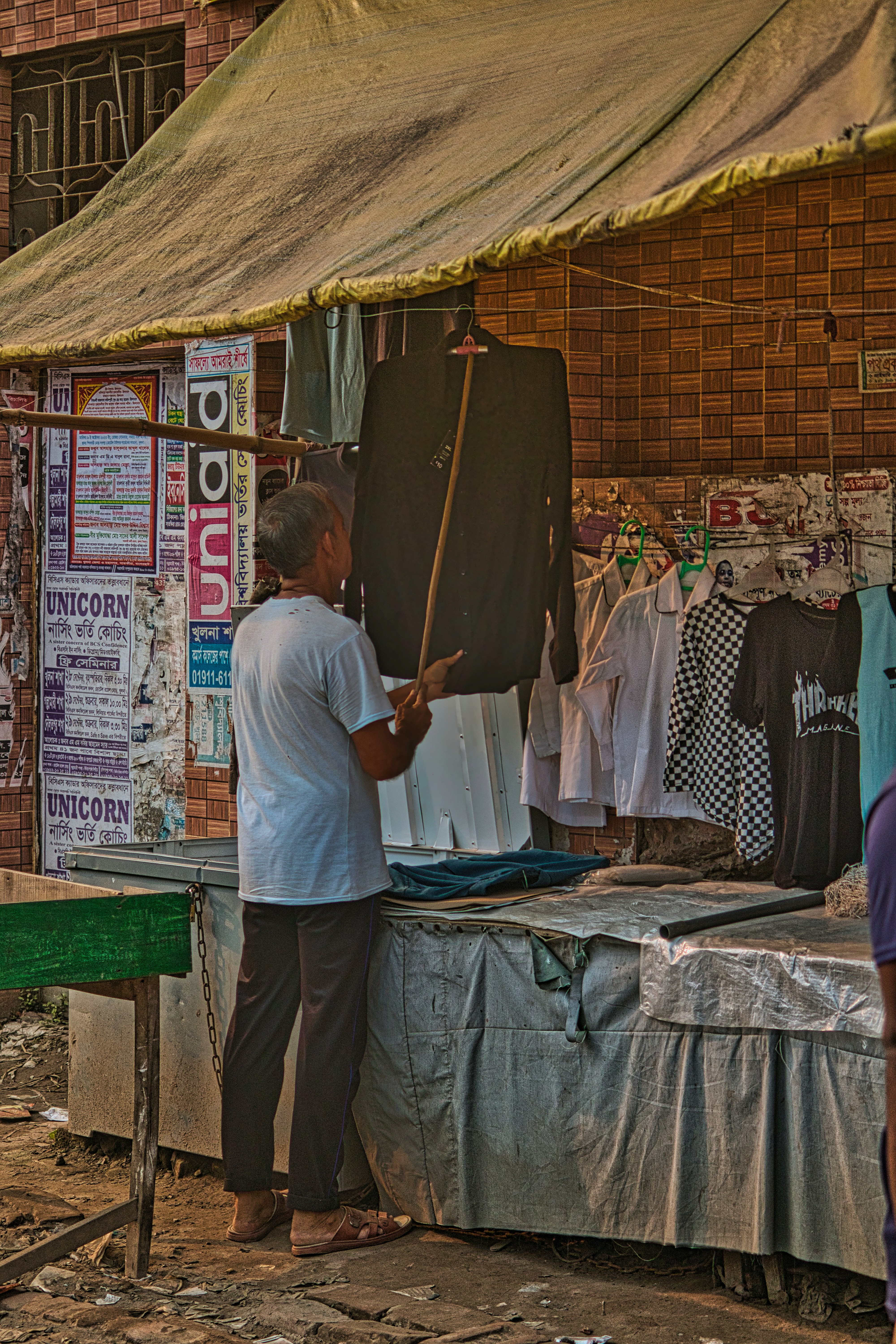 a man standing in front of a table with clothes on it