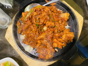 A sizzling stir-fry dish with bright vegetables and tender meat on a dark plate.