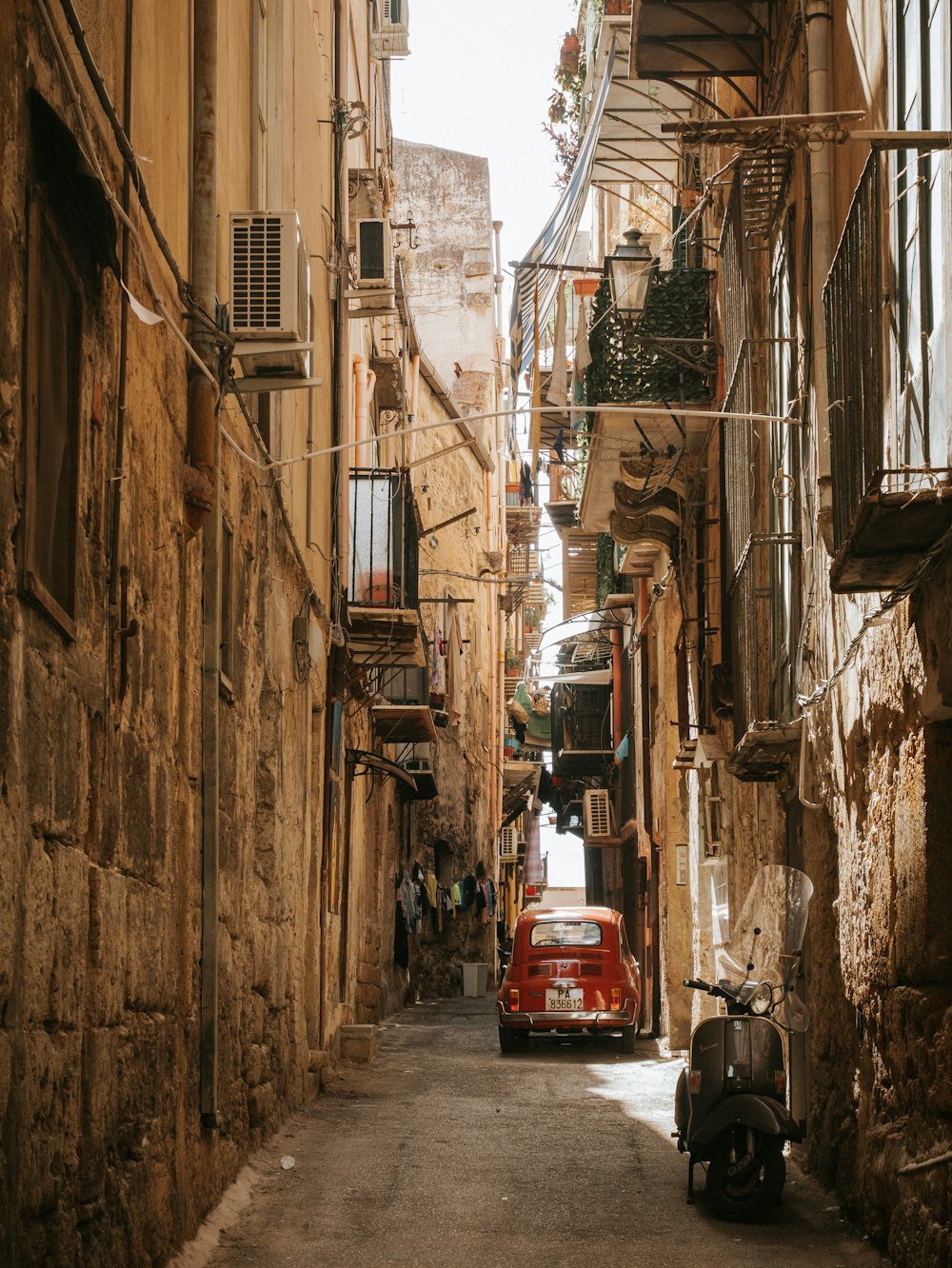 a narrow street with a scooter parked on the side of it