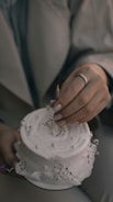 Close-up of hands arranging a wedding cake decoration.