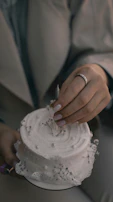 A close-up of a hand placing a golden topper on a beautifully crafted birthday cake.