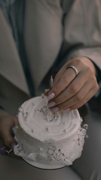Close-up of hands arranging a wedding cake decoration.