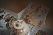 A close-up of a hand holding a beautifully crafted visiting card with delicate floral designs.