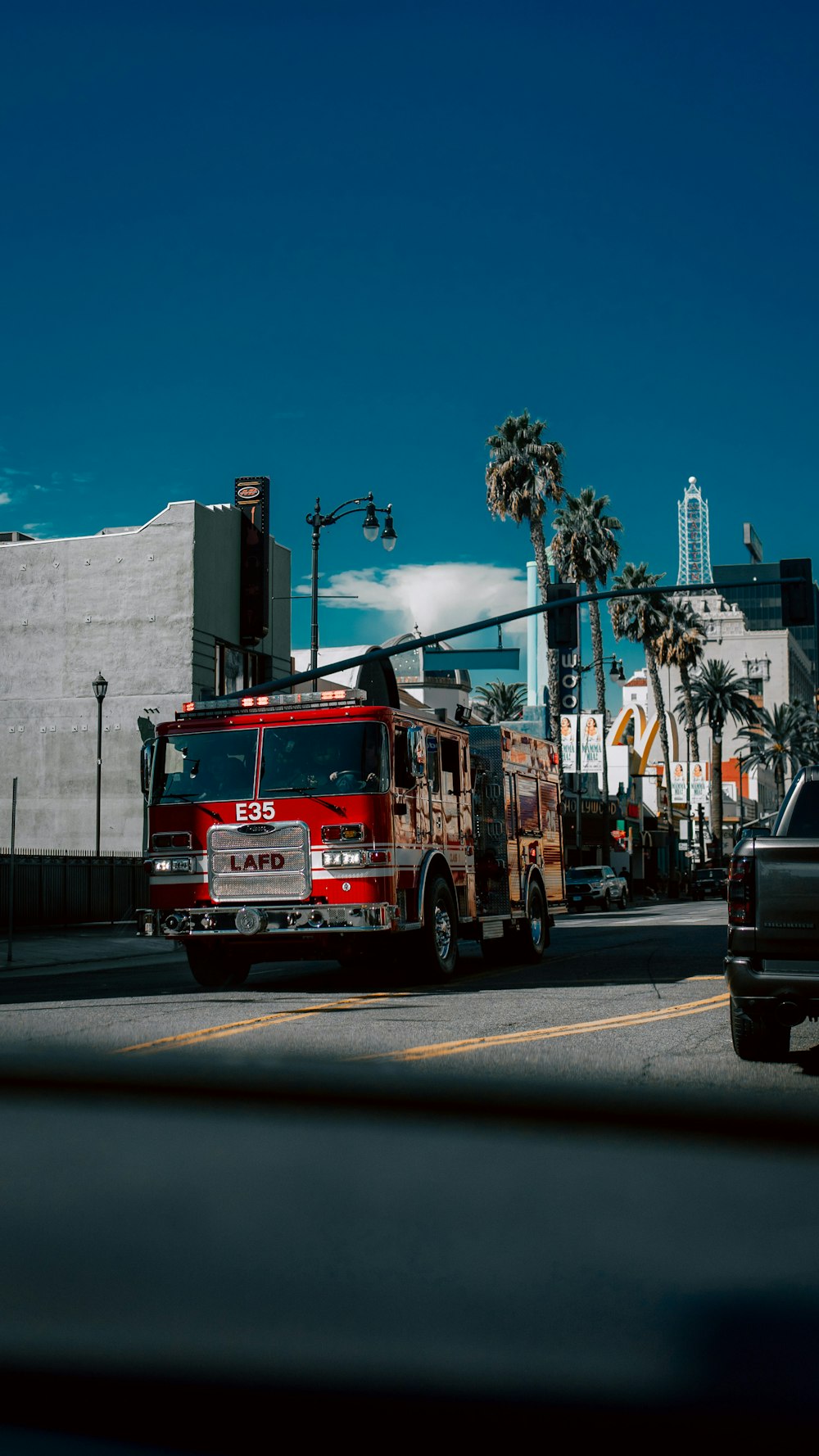 a red fire truck driving down a street next to a tall building