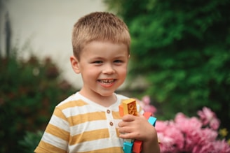 A smiling child proudly holding a completed colorful block structure.