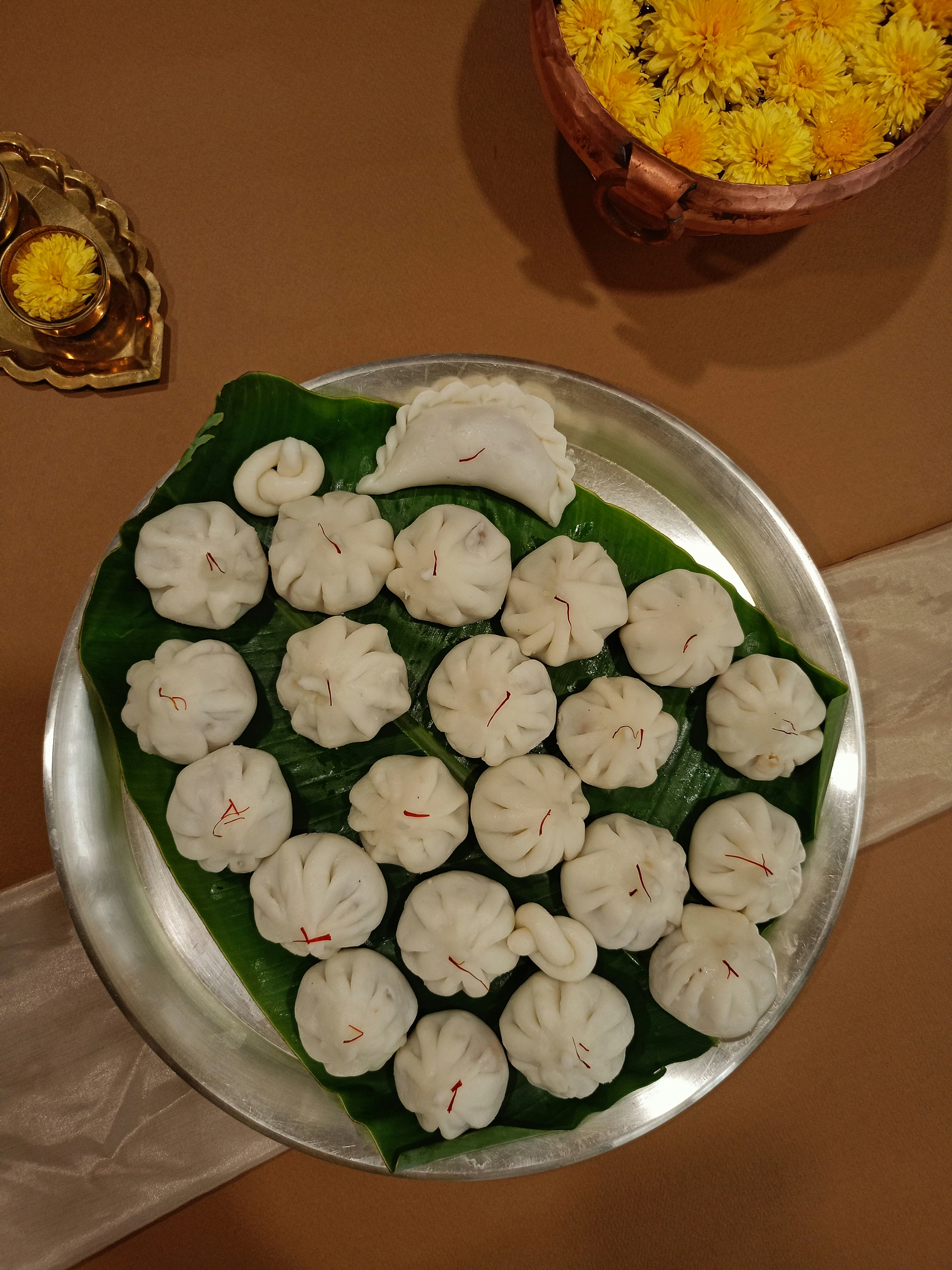 White steamed Ukdiche Modak on a banana leaf with coconut and jaggery filling visible