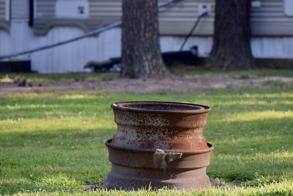 a rusted pot sitting on top of a lush green field