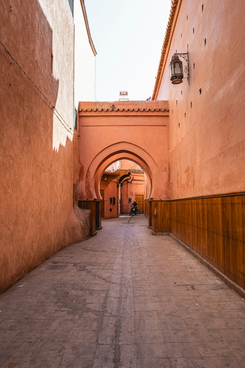 a narrow alley way with a person sitting on a bench