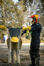 A rider adjusting their helmet, ready to hit a gravel path surrounded by autumn trees.