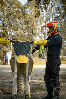 A rider adjusting their helmet, ready to hit a gravel path surrounded by autumn trees.