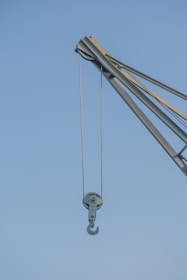 A detailed close-up of a heavy-duty crane lifting construction materials on a sunny day.