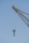 A close-up view of a crane with a metal hook hanging from it against a clear blue sky. The crane is industrial in design, made of sturdy metal with ropes or cables for lifting heavy objects.
