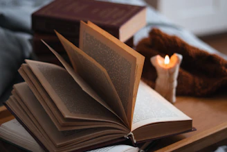 an open book sitting on top of a table next to a candle