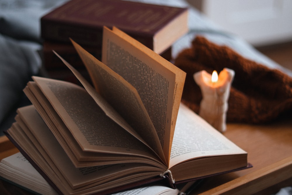 an open book sitting on top of a table next to a candle